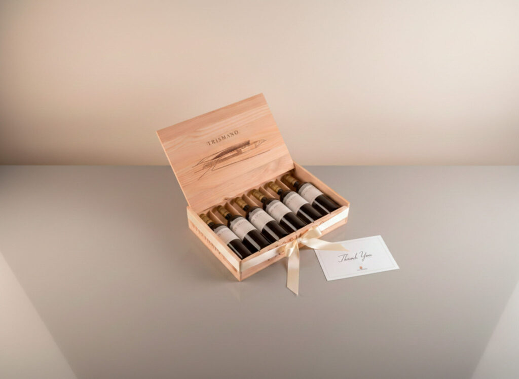 Estuche de vino premium sobre mesa neutra, con tarjeta de agradecimiento. Fondo limpio, luz cálida suave.