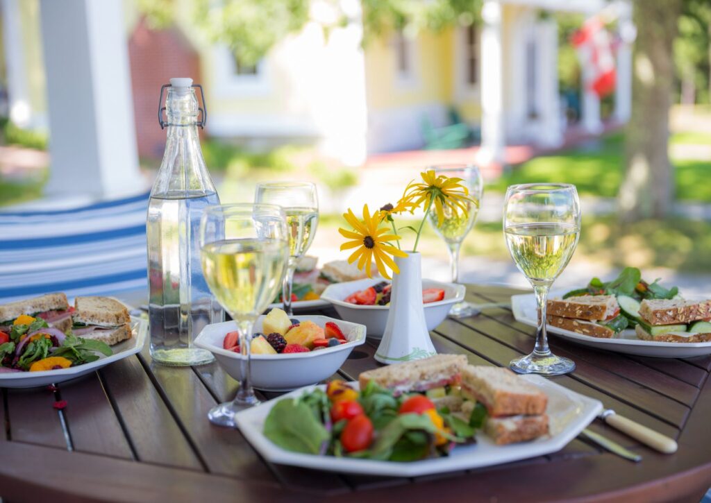 Mesa de restaurante en terraza primaveral con copas de vino blanco y platos ligeros, ideal para Semana Santa en Valencia.