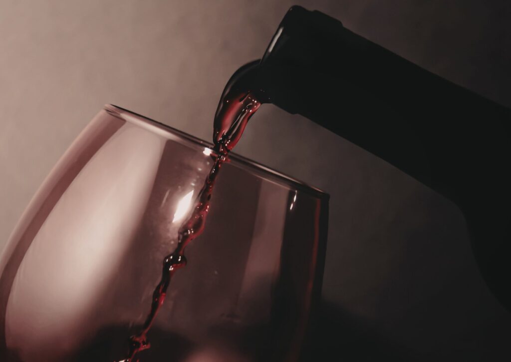 Vino tinto sirviéndose en una copa, detalle de servicio para carta de vino por copas en restaurantes.