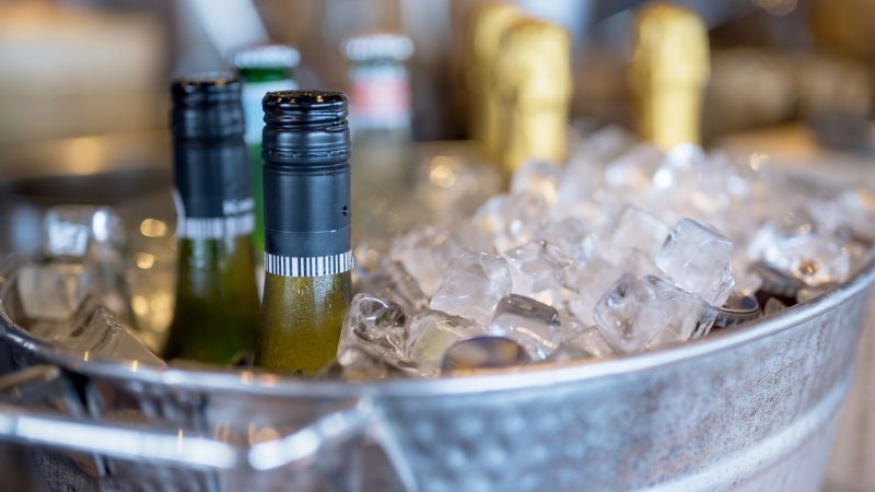 Botellas de vino en cubitera con hielo para servicio en verano, imagen para artículo sobre distribución de vino en Valencia en agosto.