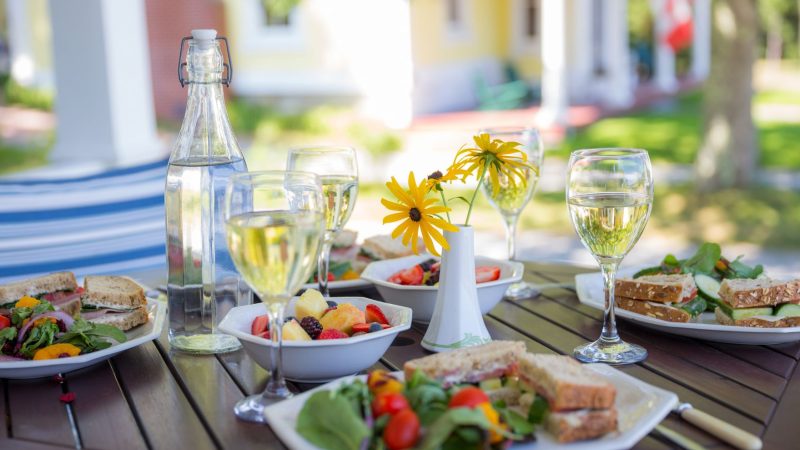 Mesa de restaurante en terraza primaveral con copas de vino blanco y platos ligeros, ideal para Semana Santa en Valencia.